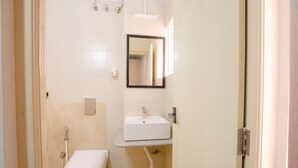 A small, clean bathroom with a toilet, sink, and mirror. - Covie Karle Town 220 (Bengaluru)