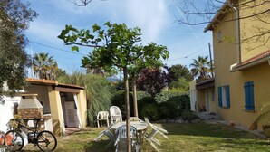 Un jardin avec un petit arbre, du mobilier d’extérieur et un vélo.