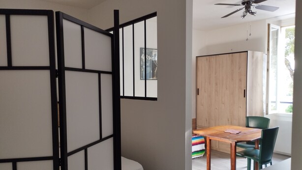Une pièce avec un lit, une table en bois et une chaise verte.