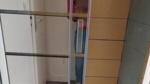 Un espace douche doté d’une porte en verre, d’un sol carrelé et d’un tapis bleu à l’entrée.