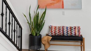 A staircase with a black railing, a wall-mounted abstract painting, a potted plant, and a bench with colorful cushions. - Designer Oasis minutes from Scottsdale Events - Heated Pool - Hot Tub - Sleeps 8 (Scottsdale)
