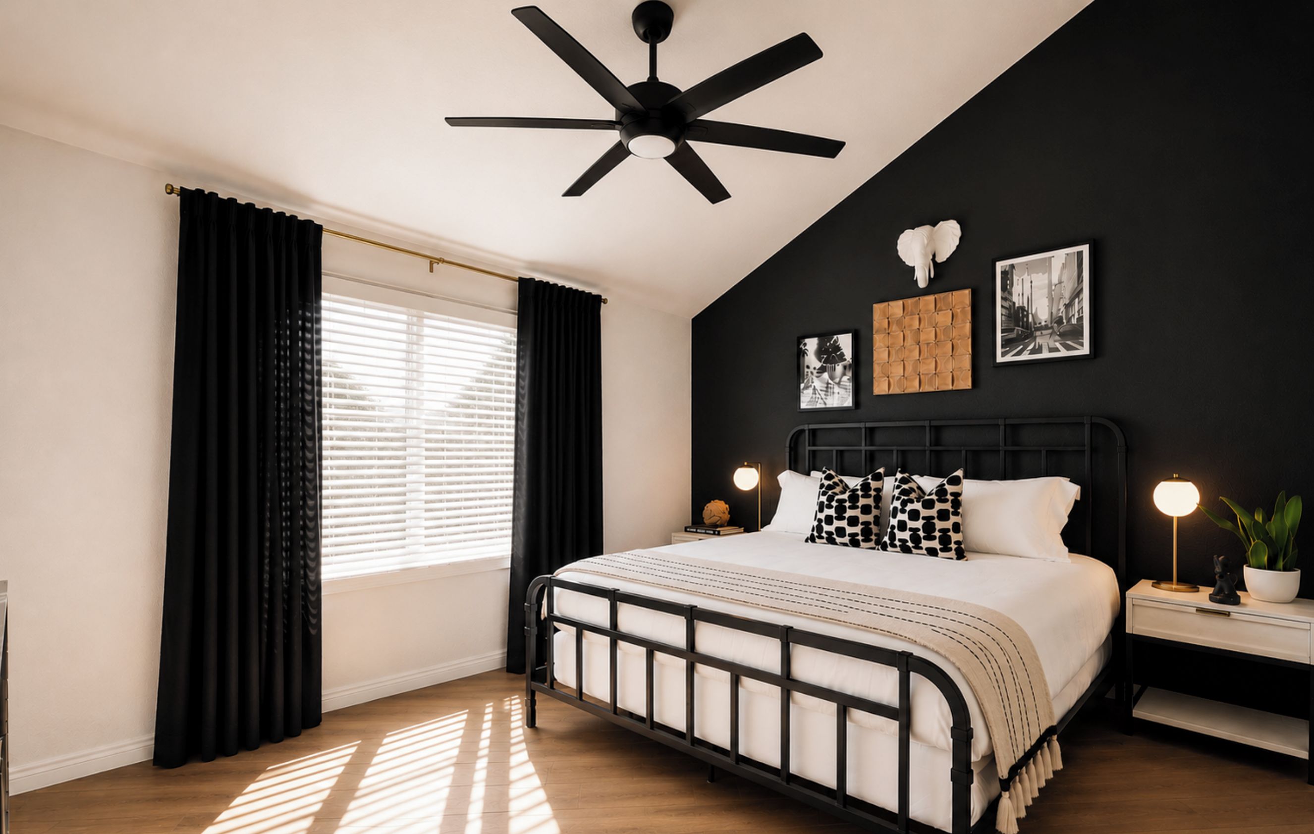 Una camera da letto con un letto, una ventola a soffitto, un comodino con una lampada e una finestra con tende.