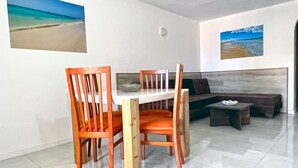 A dining area with a white table and wooden chairs, a sofa, and a small table with a bowl.
