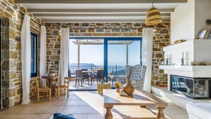 A room with stone walls, a wooden table, a sofa, and a fireplace.