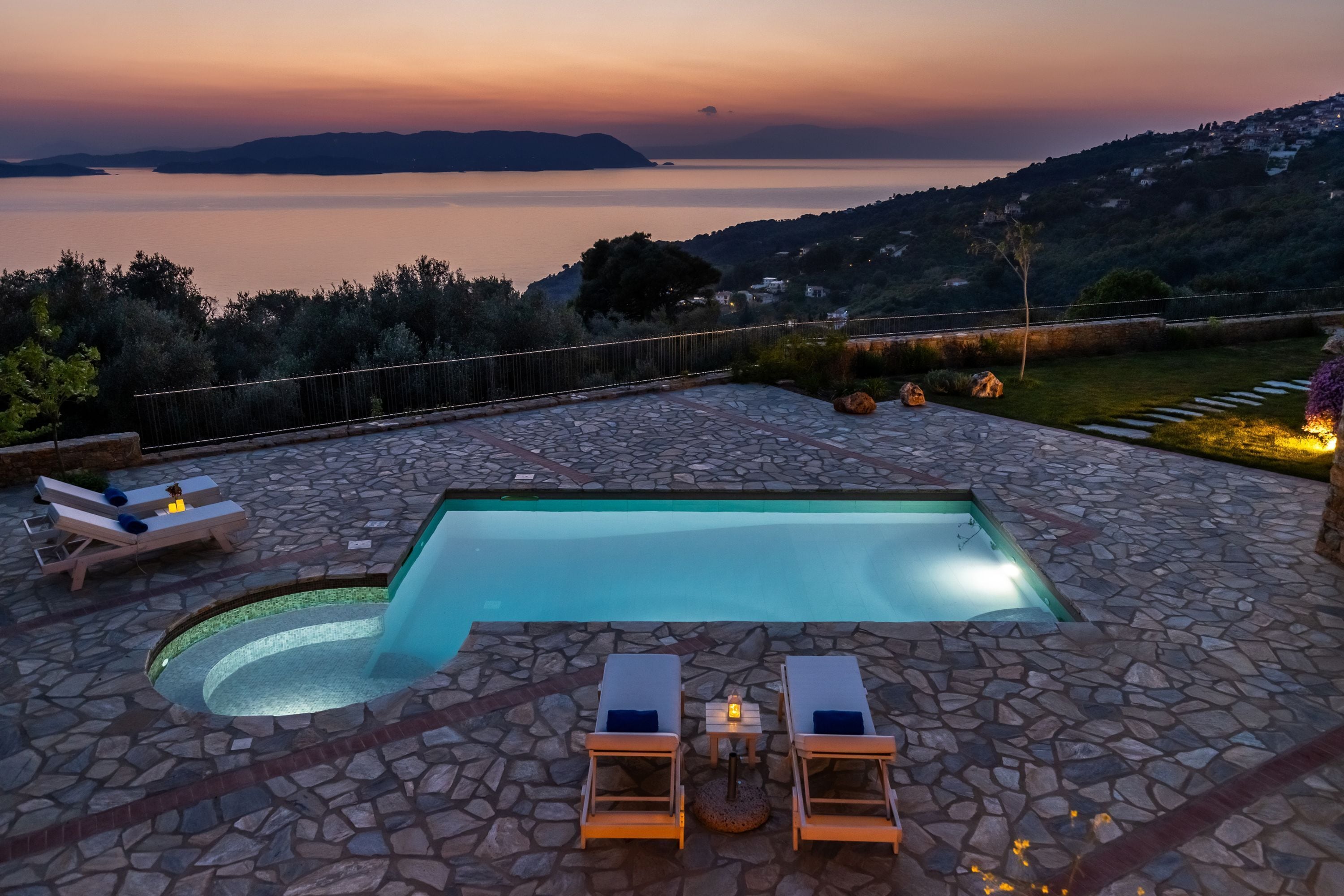 En swimmingpool med liggestole og en flisebelagt terrasse.