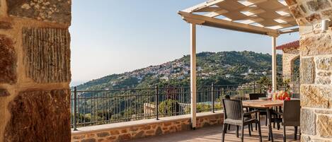 A terrace with stone walls, a pergola, and a table with chairs.