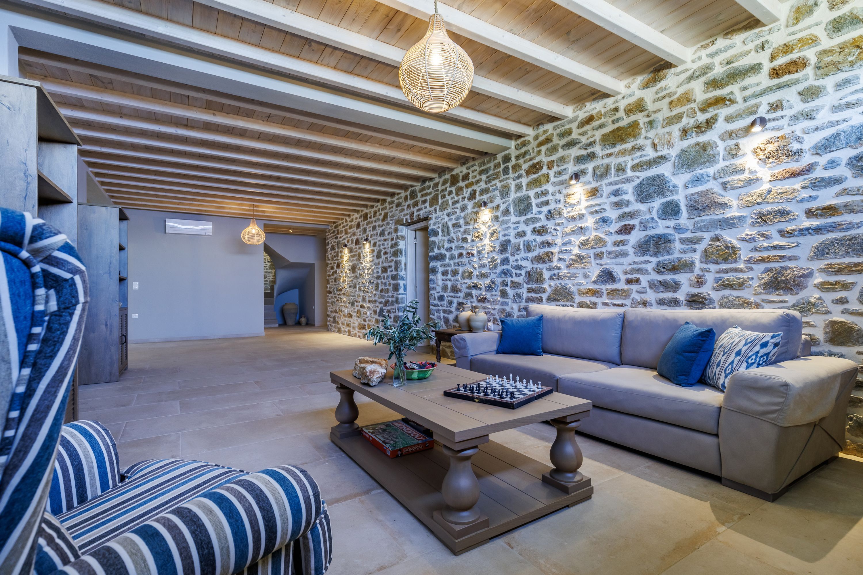 A cozy living room with a stone wall, a sofa, a coffee table, and a chessboard.