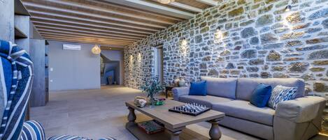 A cozy living room with a stone wall, a sofa, a coffee table, and a chessboard.