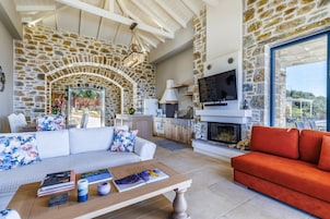 Una sala de estar con pared de piedra, chimenea, sofá y un sofá rojo, además de una televisión.