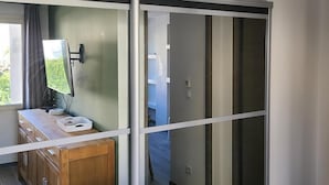A modern room with a sliding glass door, a wooden cabinet, a desk with a computer monitor, and a ceiling-mounted air conditioner. - Appartement Dans une Résidence ART Deco!! au Bord de la Plage (La Ciotat)