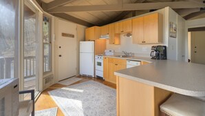 A kitchen with wooden cabinets, a white refrigerator, a stove, and a sink. - Cozy rental near Greenbrier Resort with a deck, stunning views modern-rustic charm, and full kitchen (White Sulphur Springs)