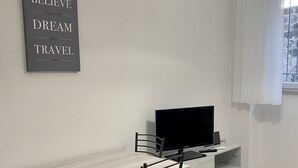 A modern, minimalistic room with a desk, two chairs, a flat-screen TV, and a motivational quote on the wall. - Daisy Apartment (Piano di Sorrento)