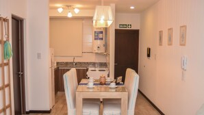 A hotel room with a dining area featuring a table and chairs, a water heater, a sink, and a door marked 'SALIDA'.
