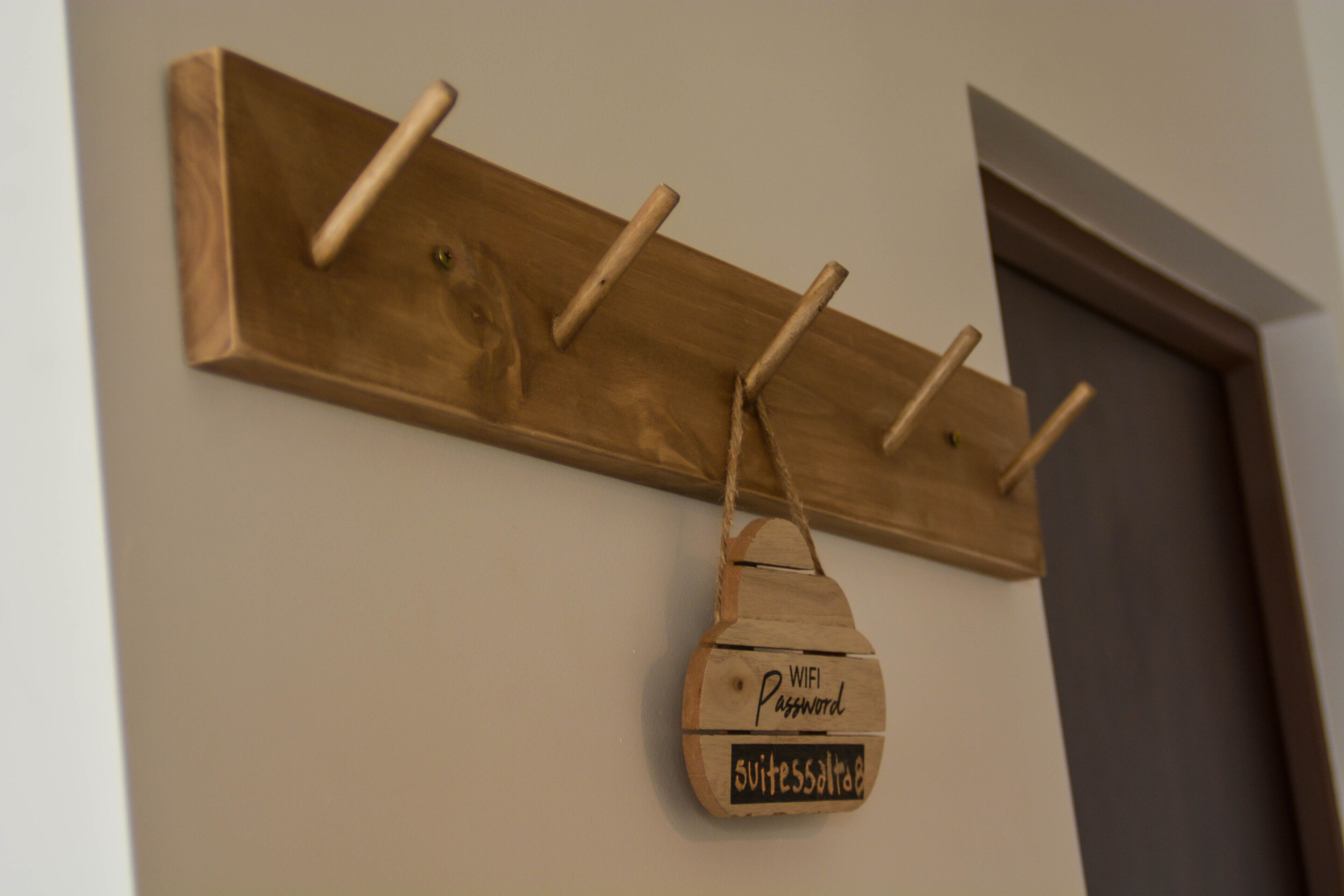 Un porte-manteau en bois muni de crochets et d’un sac suspendu portant les inscriptions « Mot de passe WIFI » et « suitemaster ».