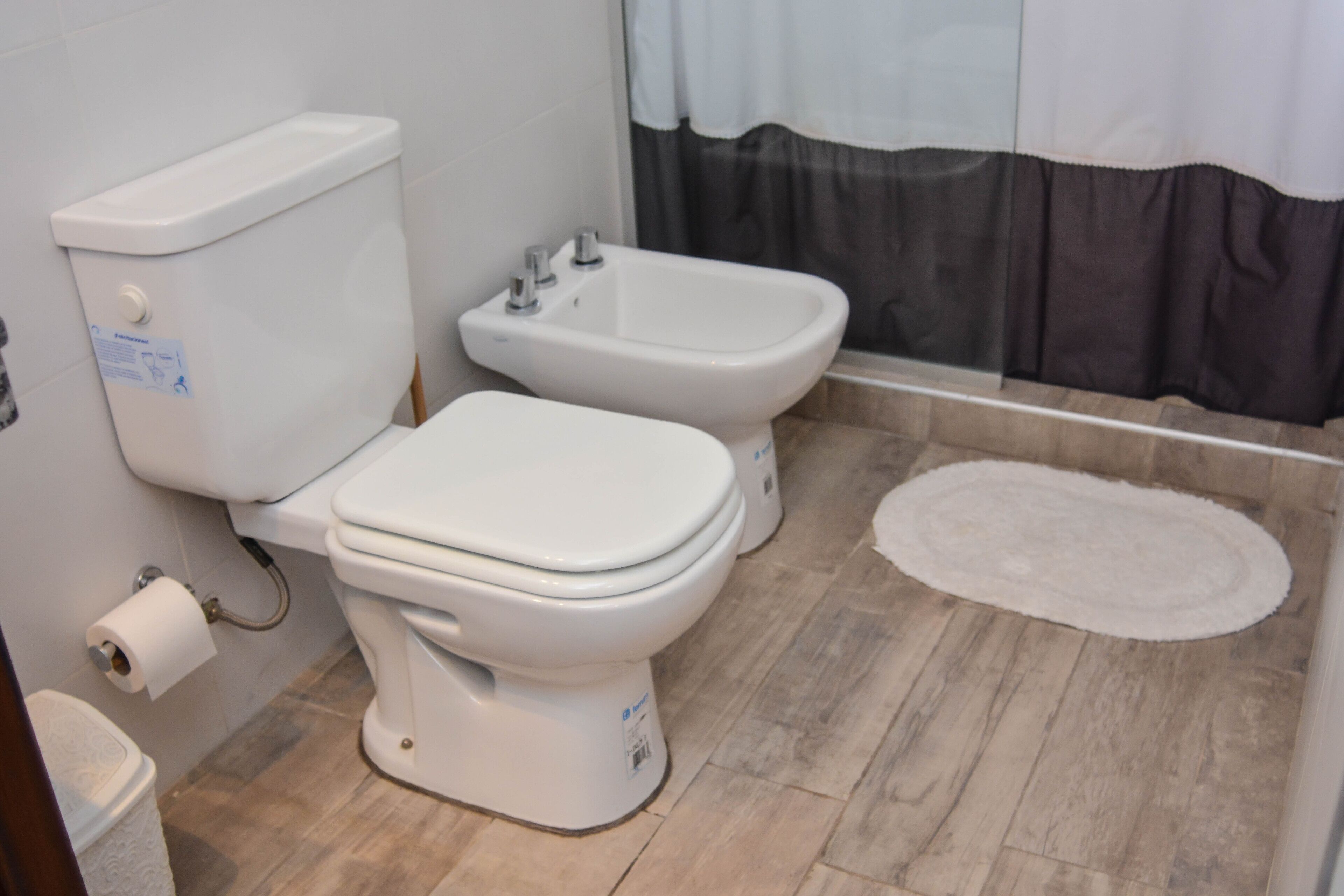 A modern bathroom with a toilet, bidet, and a small rug on the floor.