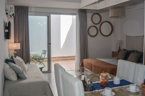 A hotel room with a bed, a sofa, a dining table with cups and a jar, and a view of the outdoors. - Suites Salta  (Salta)