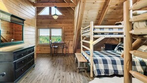 A cozy cabin interior with a bunk bed, wooden dresser, and a desk with chairs. - Near Pigeon Forge | Theater, Game Room, Hot Tub & Resort Pools (Sevierville)