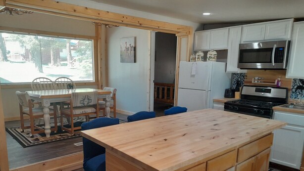 Eine moderne Küche mit Holzschränken, einer zentralen Kochinsel und einem Essbereich mit Tisch und Stühlen.
