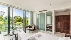 A spacious bedroom with a large bed, a desk, and a view of a lush garden through floor-to-ceiling windows. - Enjoy Boutique Hotel & Restaurat (Siem Reap)