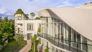 A modern building with a curved facade, large windows, and a central staircase. - Enjoy Boutique Hotel & Restaurat (Siem Reap)