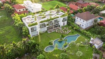 Una casa moderna con piscina, rodeada de exuberante follaje y palmeras.