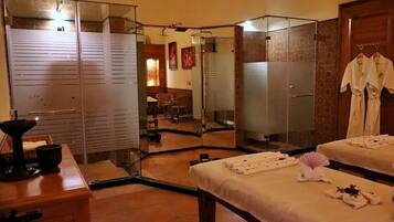 Une salle de spa équipée de deux tables de massage, d’un miroir et d’un petit coin salon avec une chaise et une table.