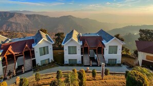 A row of white houses with steep roofs and a view of distant mountains. - Vatsyayana Resorts (Salt)