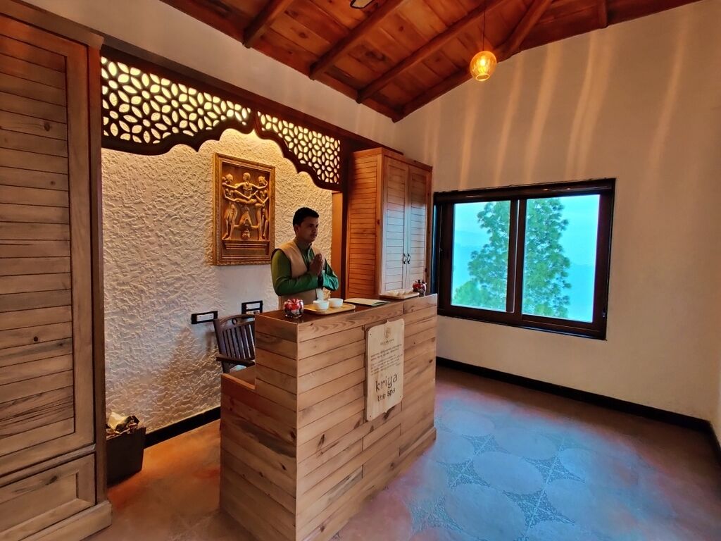 A reception desk with a wooden finish, a decorative wall, and a window with a view of trees.