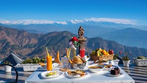 A table set with food and drinks on a terrace with a mountain view. - Vatsyayana Resorts (Salt)