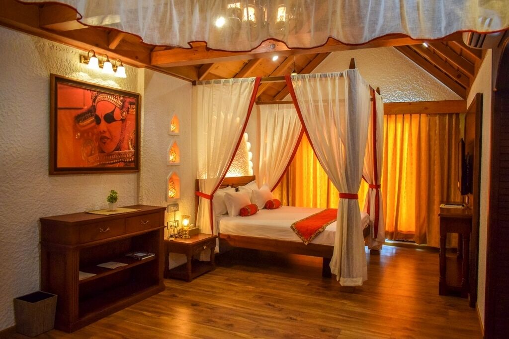 A bedroom with a canopy bed, wooden furniture, a bedside table with a lamp, and a framed picture on the wall.
