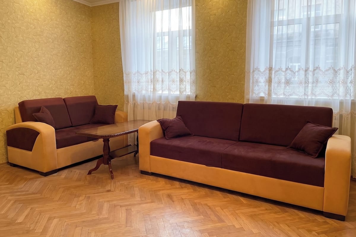 Una habitación con dos sofás, una mesita y papel tapiz estampado.