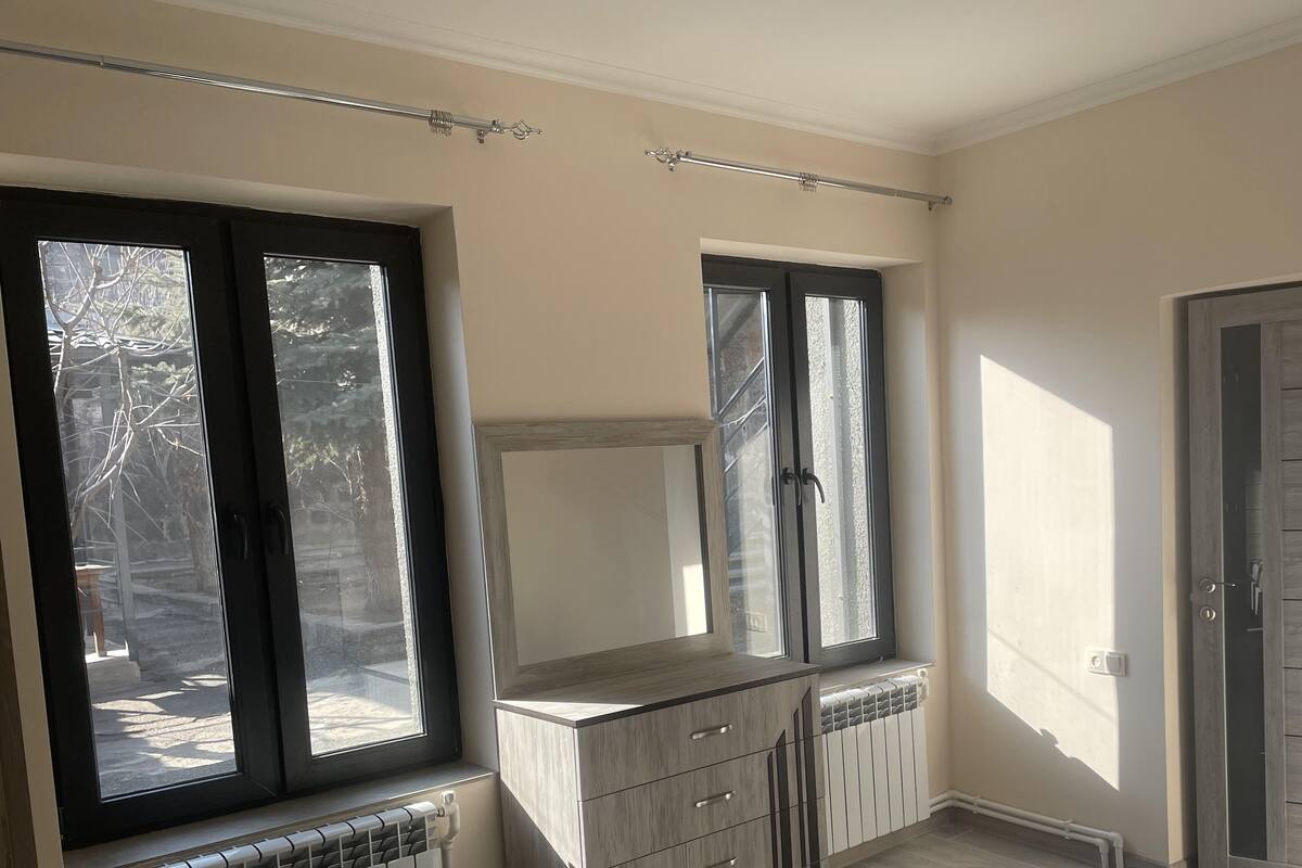 Un baño con ventana, radiador y puerta.