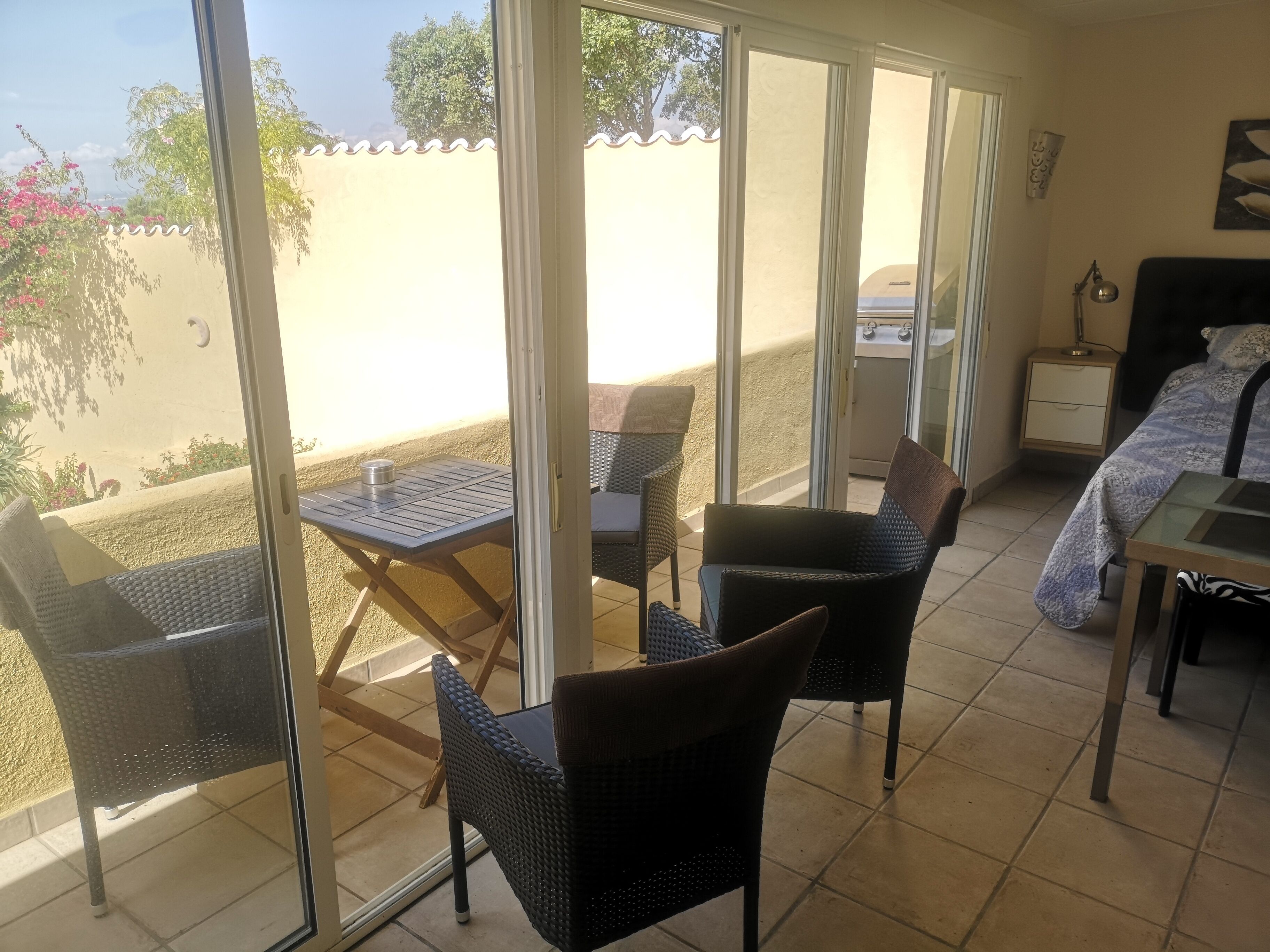 A room with a balcony, a bed, a table, and chairs.