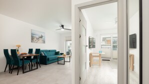 Un saló modern amb un sofà color turquesa, una taula de menjador amb caires i un quadre a la paret.