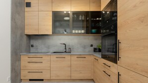 Una cuina moderna amb armaris de fusta, un rentatlle d'acer inoxidable i un forn negre.
