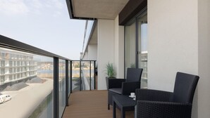 Un balcó amb mobles de vimet, una planta en test i vista a una zona de construcció.