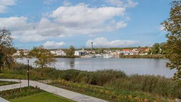 A riverside view with a paved walkway, buildings, and a small dock.