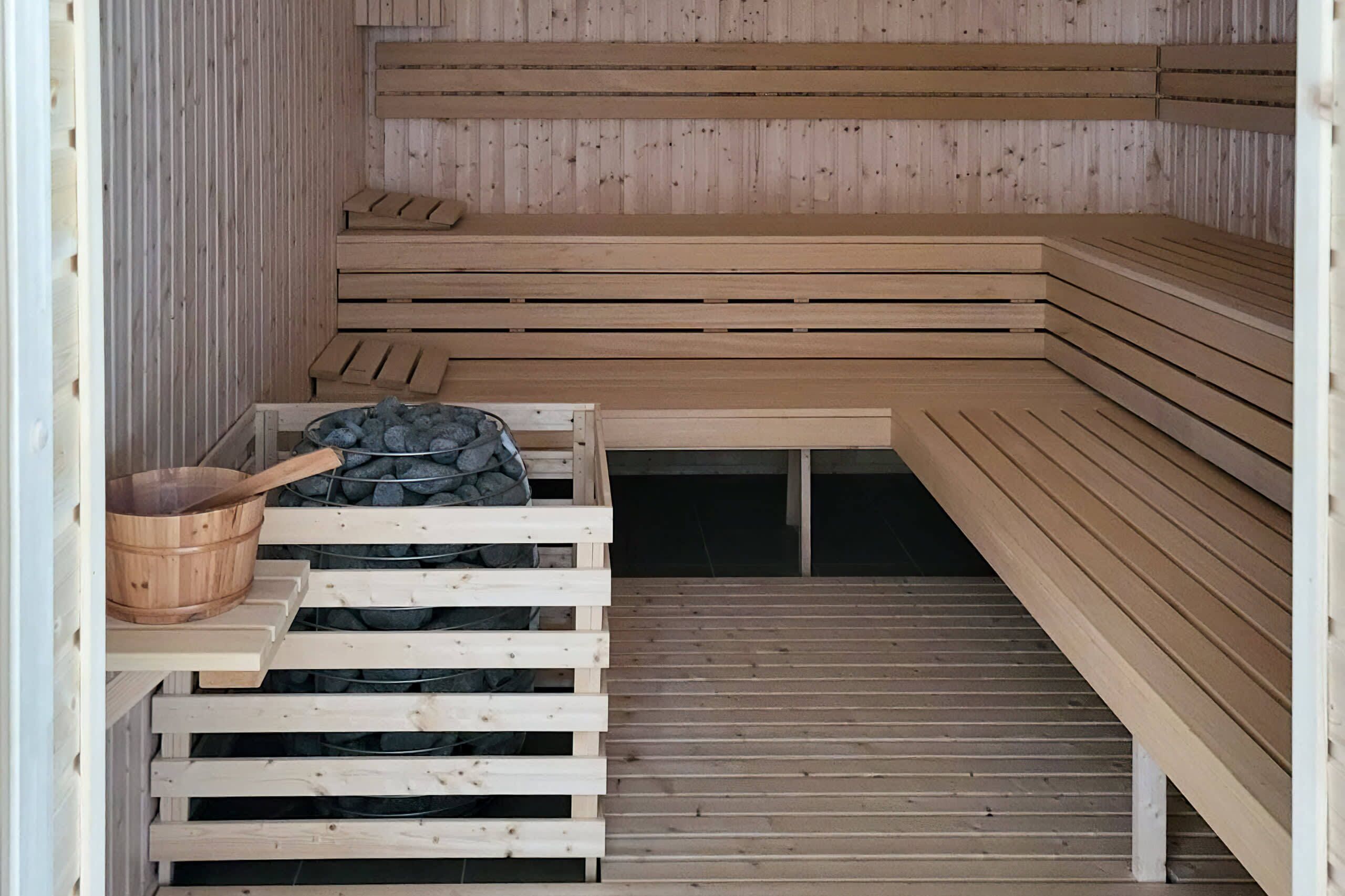 A sauna with wooden benches and a stone heating element.