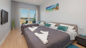Habitación de hotel con una cama grande, televisión, un cuadro y vistas al exterior.