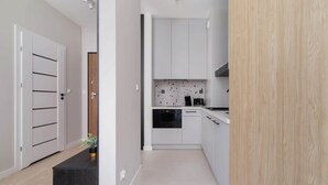 A modern kitchen with white cabinets, a black countertop, and a backsplash with a speckled pattern. - Tasteful Studio | Balcony | Workspace (Kraków)
