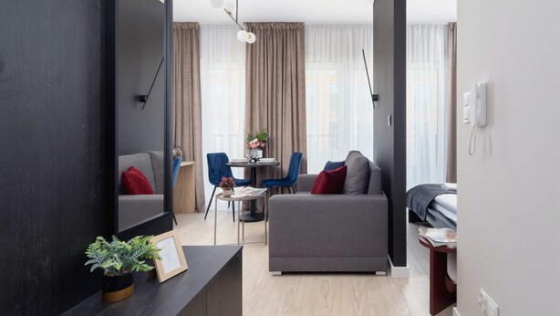 A modern living room with a sofa, a dining table, and a TV. - Tasteful Studio | Balcony | Workspace (Kraków)