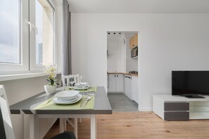 Una cocina moderna con armarios blancos, un microondas y un comedor con una mesa para dos.