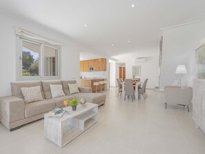 A modern living room with a sofa, coffee table, and dining area.