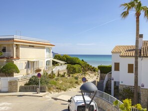 A coastal property with a white building, a parked vehicle, and a clear view of the sea.