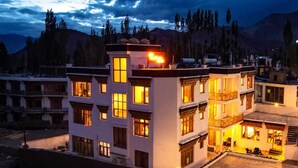 A multi-story hotel with a modern architectural design, featuring balconies and a rooftop terrace.