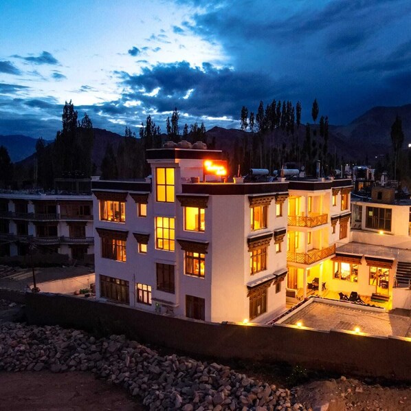 A multi-story hotel with a modern architectural design, featuring balconies and a rooftop terrace.
