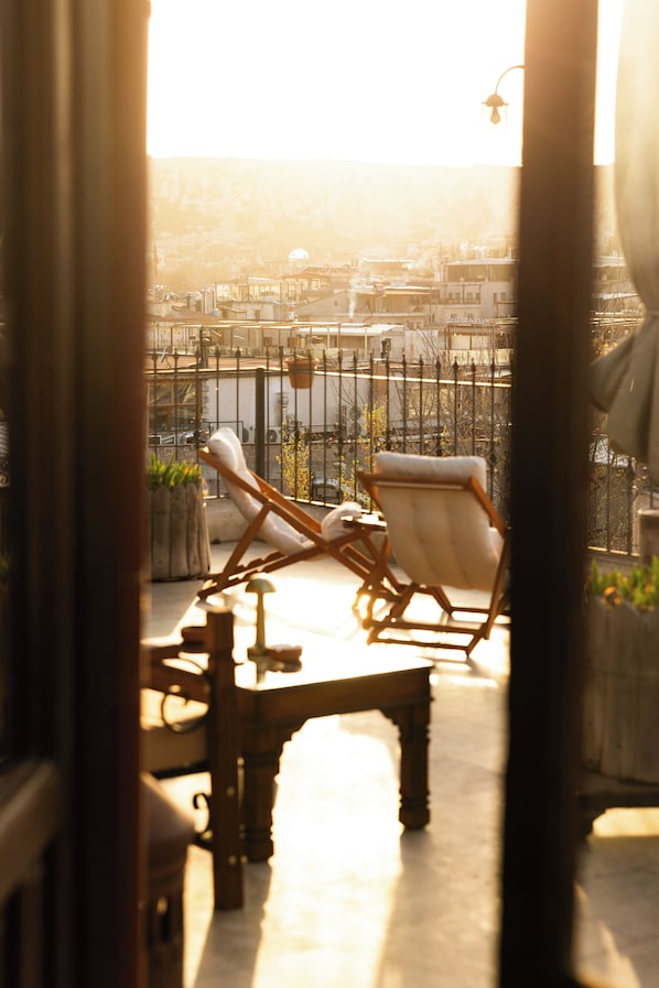 Ein Balkon mit zwei Liegestühlen und einem Tisch, mit Blick auf eine Stadtlandschaft mit Gebäuden und einem Zaun.
