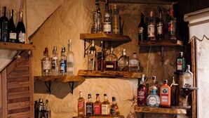Eine Bar mit Regalen voller Spirituosenflaschen, Holzregalen und einer rustikalen Steinwand.