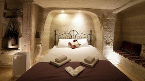 Dormitorio con paredes de piedra, cama, almohadas, toallas y un calentador.