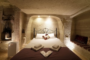 Dormitorio con paredes de piedra, cama, almohadas, toallas y un calentador.
